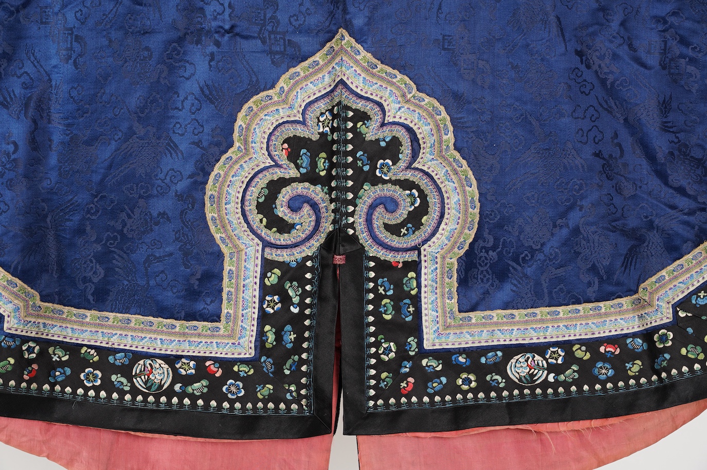 A late 19th century Chinese blue silk damask jacket, woven with Phoenix and auspicious symbols. The jacket edged with ornate rows of braiding and silk embroidery, the interior with original pink silk lining. The jacket f
